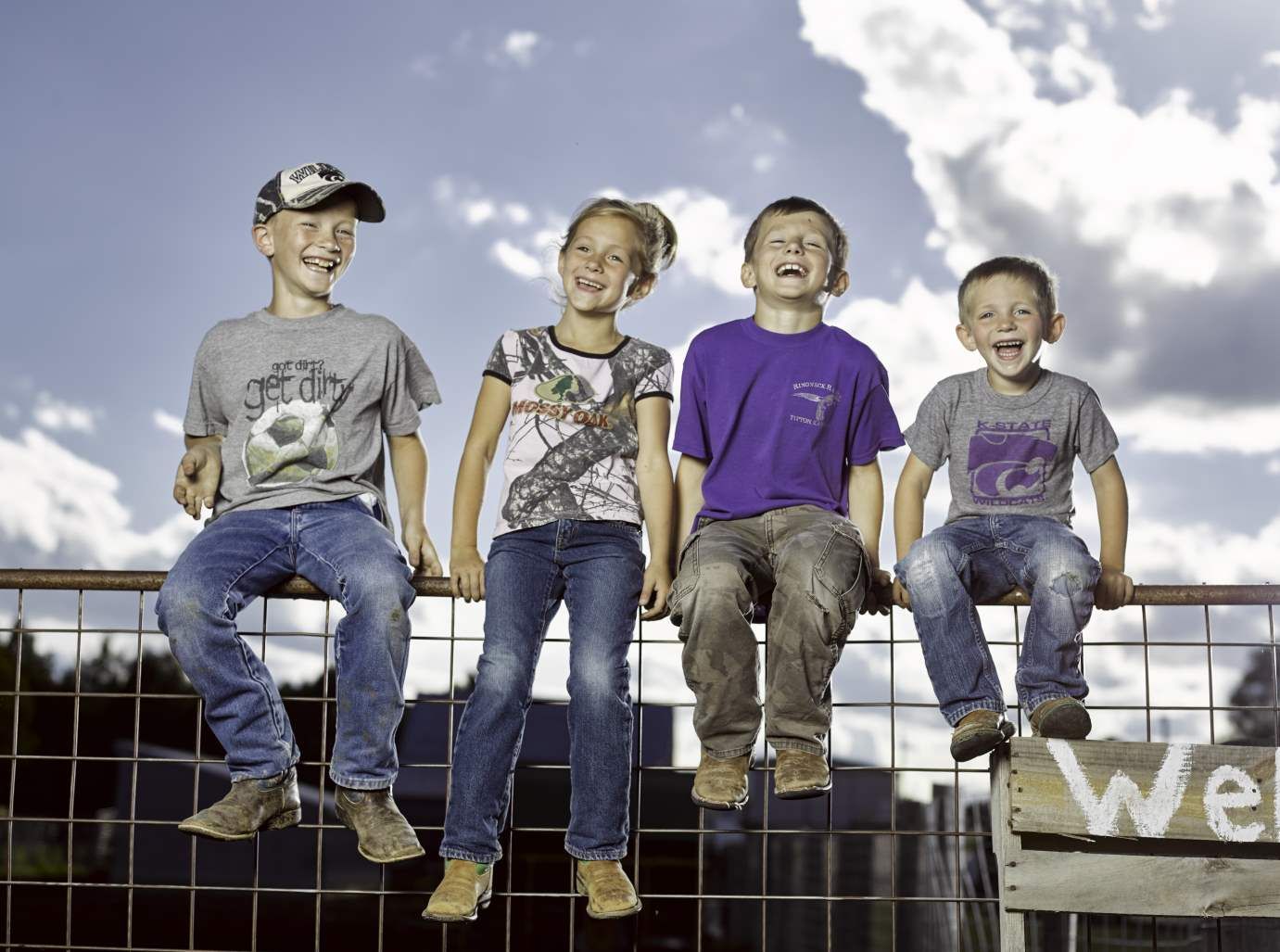 Kids sitting on a fence.