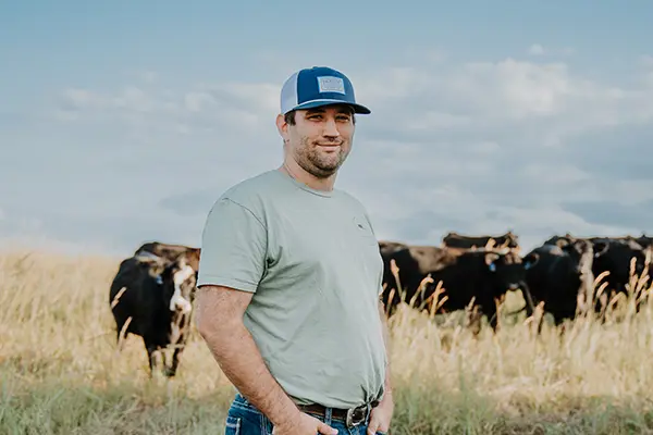 Rancher standing in a field with cattle in the background
